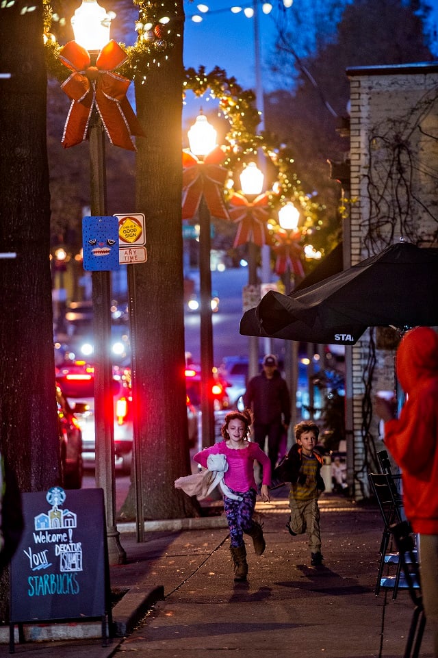 Stella Florence (left) and her brother Grant run up the street towards Little Shop of Stories before the start of the annual lighting of the tree in Decatur on Thursday. Photo: Jonathan Phillips