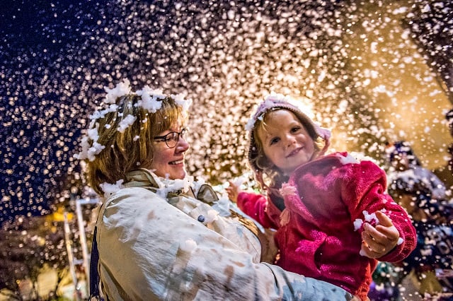 Cora Parsons (right) is held by her grandmother Maureen Sobolewski as she plays in the "snow" during the annual lighting of the tree in Decatur on Thursday. Photo: Jonathan Phillips