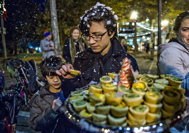 Julian Daniel (center) takes a quiche from the tray during the annual lighting of the tree in Decatur on Thursday. Photo: Jonathan Phillips